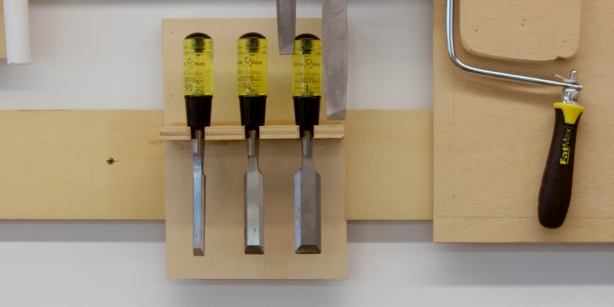 Chisels and coping saw mounted on a workshop tool wall