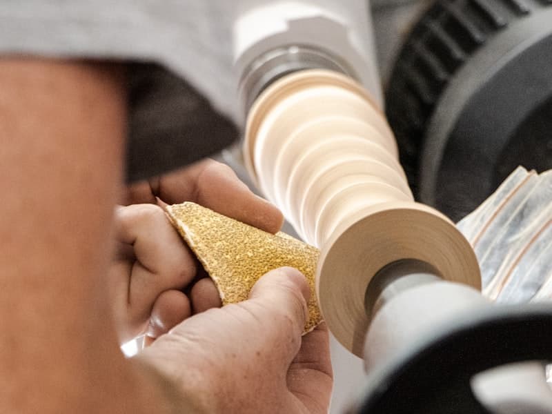 Hands sanding a wooden piece with sandpaper